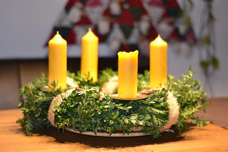 Four yellow candles decorated over a wreath