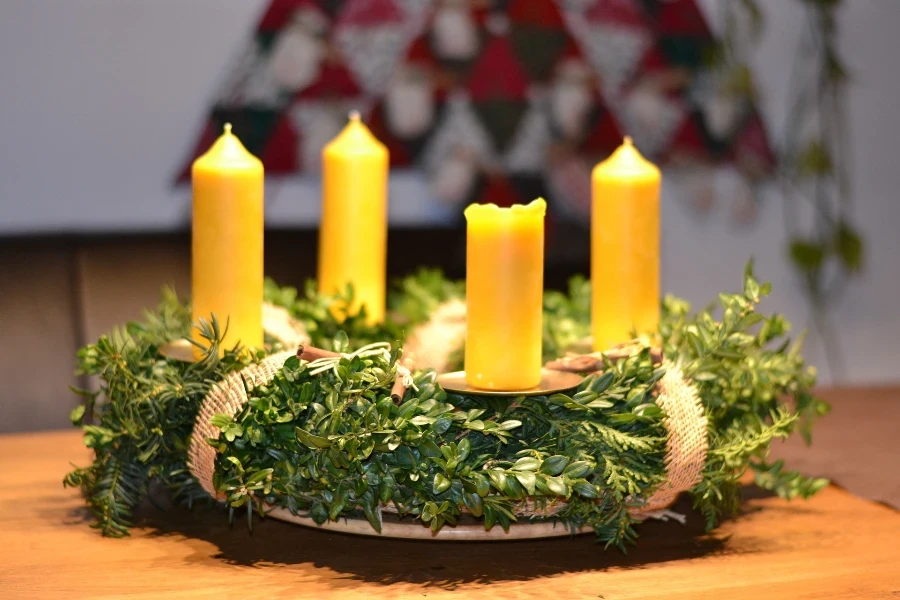 Quatro velas amarelas decoradas sobre uma guirlanda