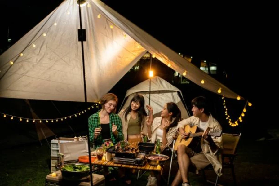 Friends under canopy at night with string of camping lights