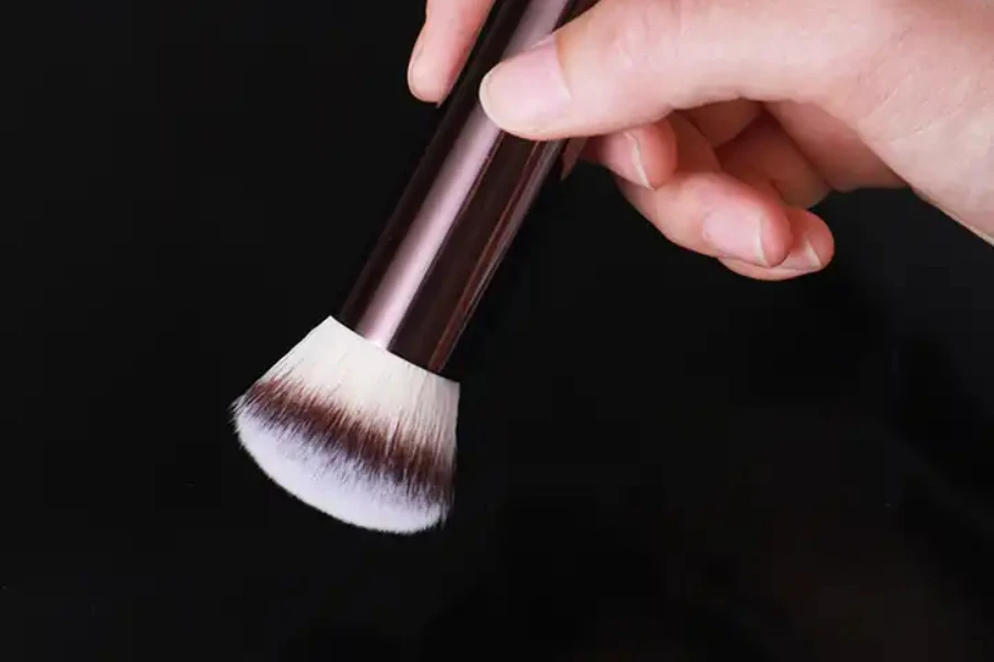 Hand holding a blush brush on a black background