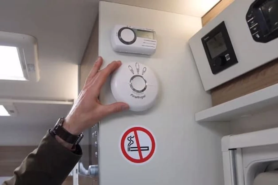 Hand touching a carbon monoxide detector in an RV
