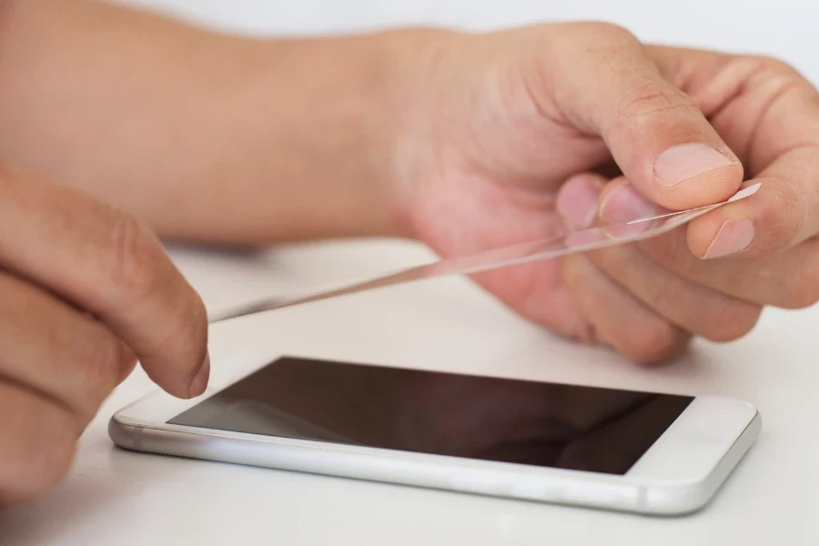 Hands applying a screen protector to a white phone