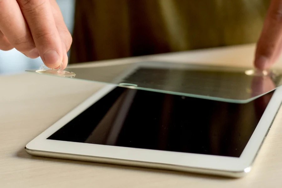 Mãos aplicando protetor de tela em um tablet