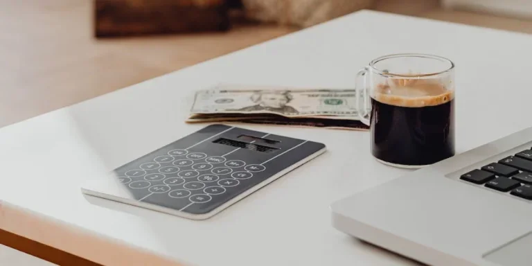 Laptop sitting on a table with cash beside it and a Christmas tree in the background