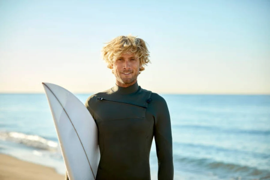 Male surfer holding board and wearing all black wetsuit