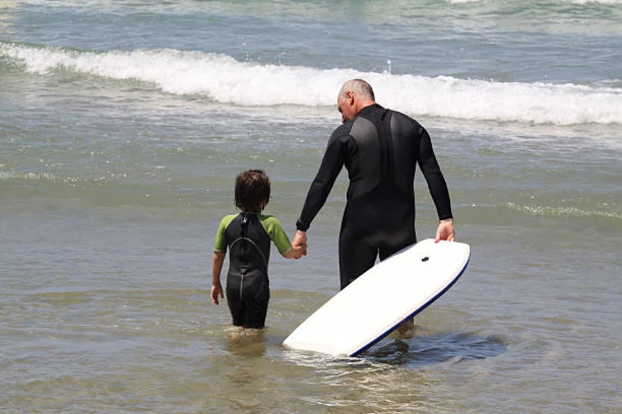 Man and child walking into water wearing semi dry wetsuits
