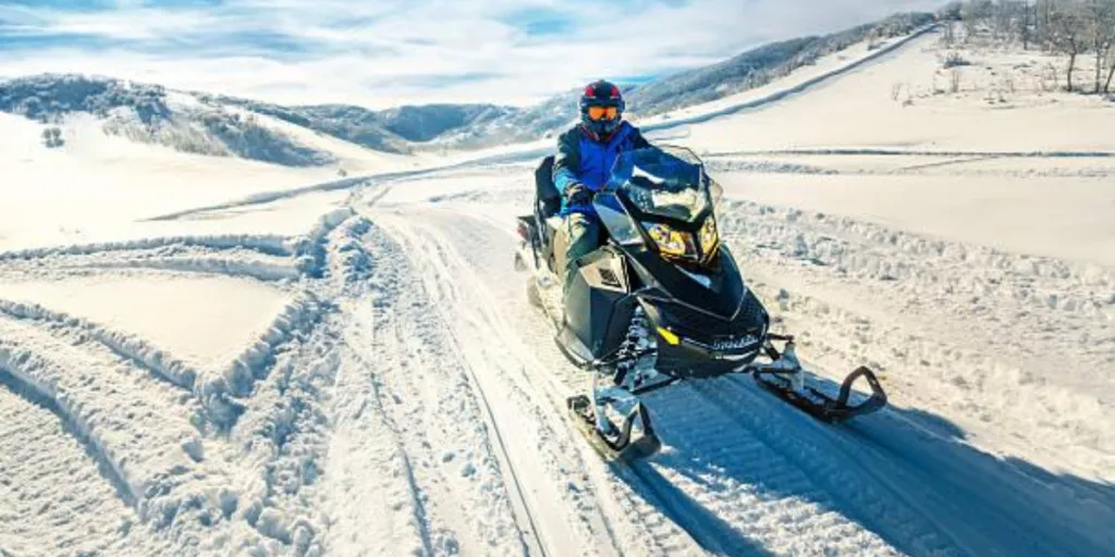 Man in full gear driving a snowmobile on a mountain