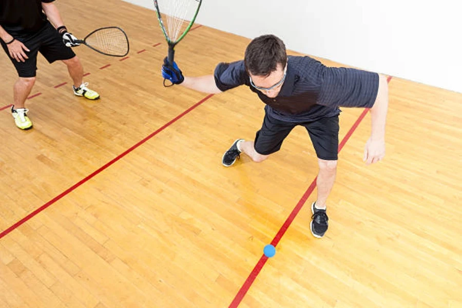 Mann schwingt einen Squashball und trägt eine starke Squashbrille