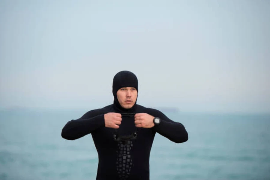 Hombre vestido con traje negro de agua fría con capucha negra