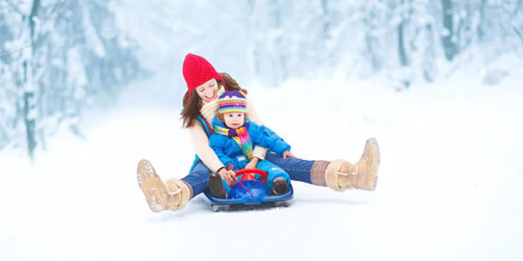 Mother sitting on blue sled for toddler with child