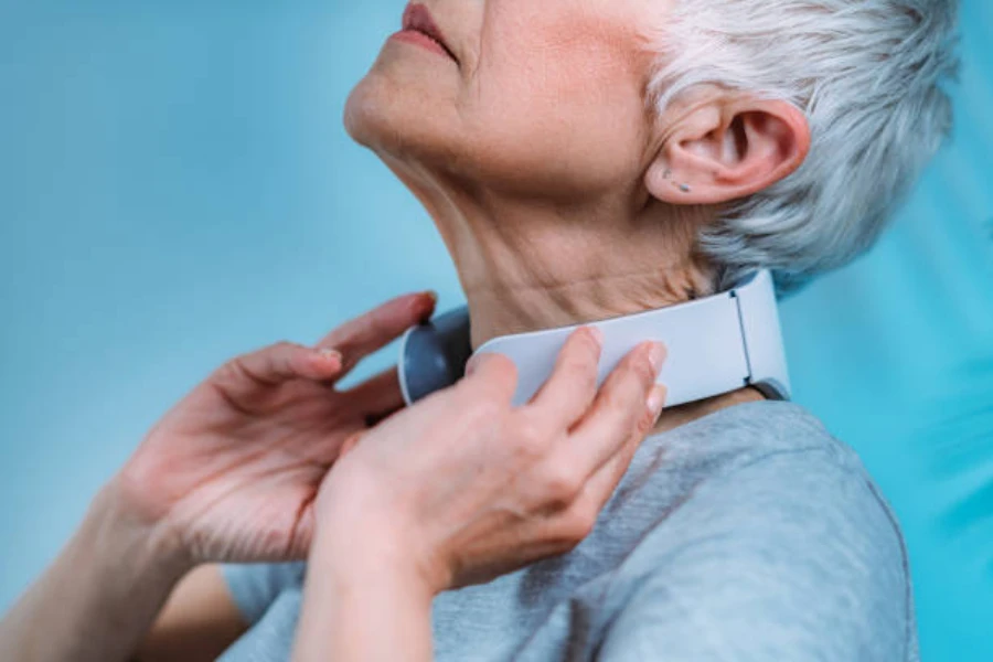 Older woman using grey neck massager to relieve pain