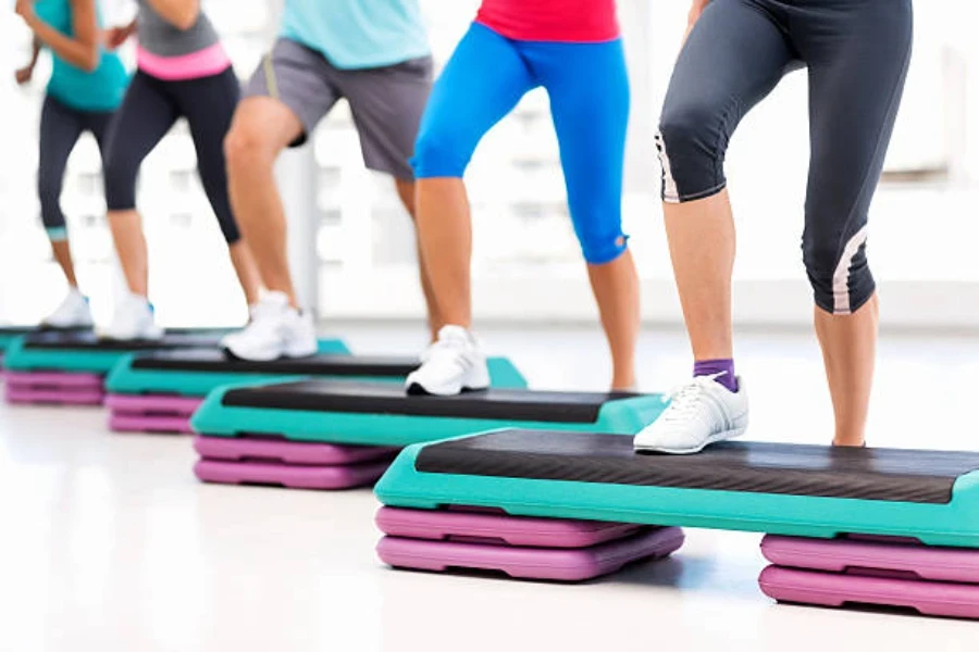 People in fitness class using aerobics steps in routine