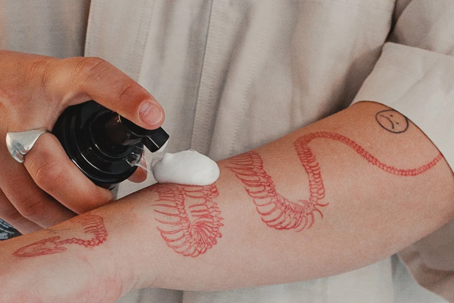 Person applying tattoo foam soap to a colored tattoo