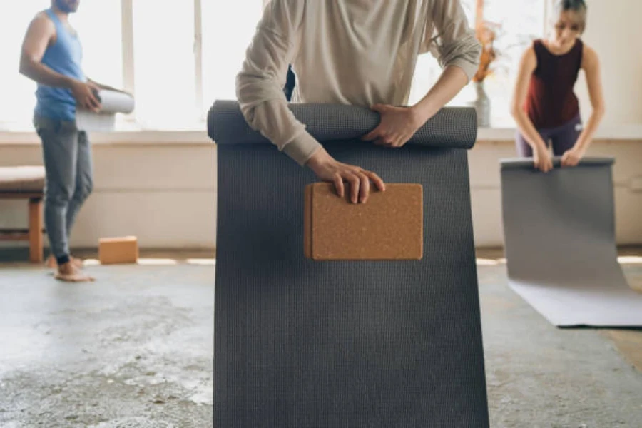 Person holding cork yoga block while rolling yoga mat