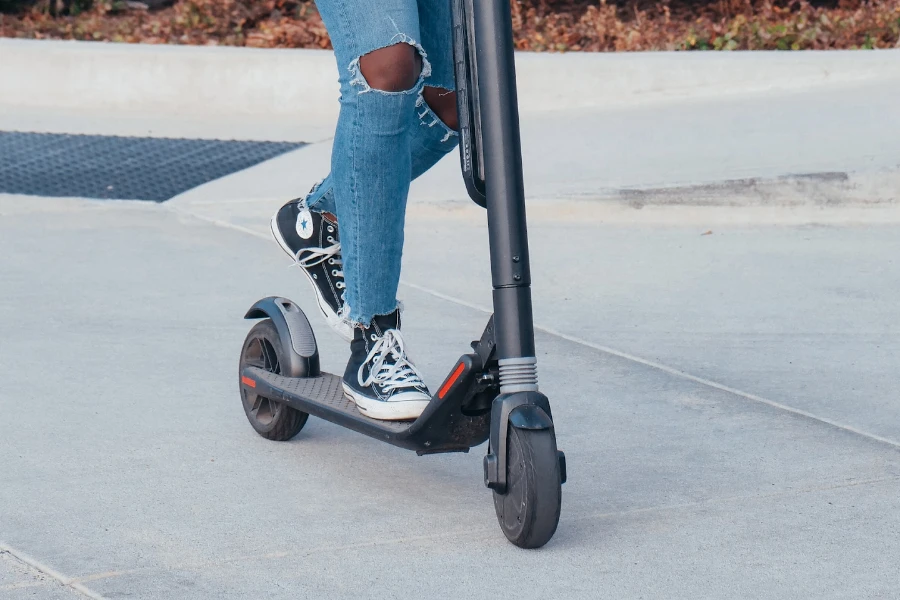 Person in blue jeans riding a black e-scooter