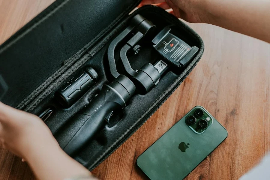 Pessoa abrindo uma caixa com um tripé, iPhone sentado na mesa ao lado