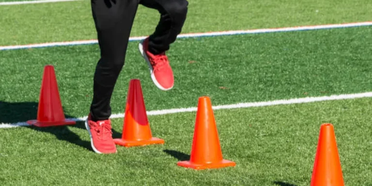 Человек бежит через конусы ловкости на поле с искусственной травой