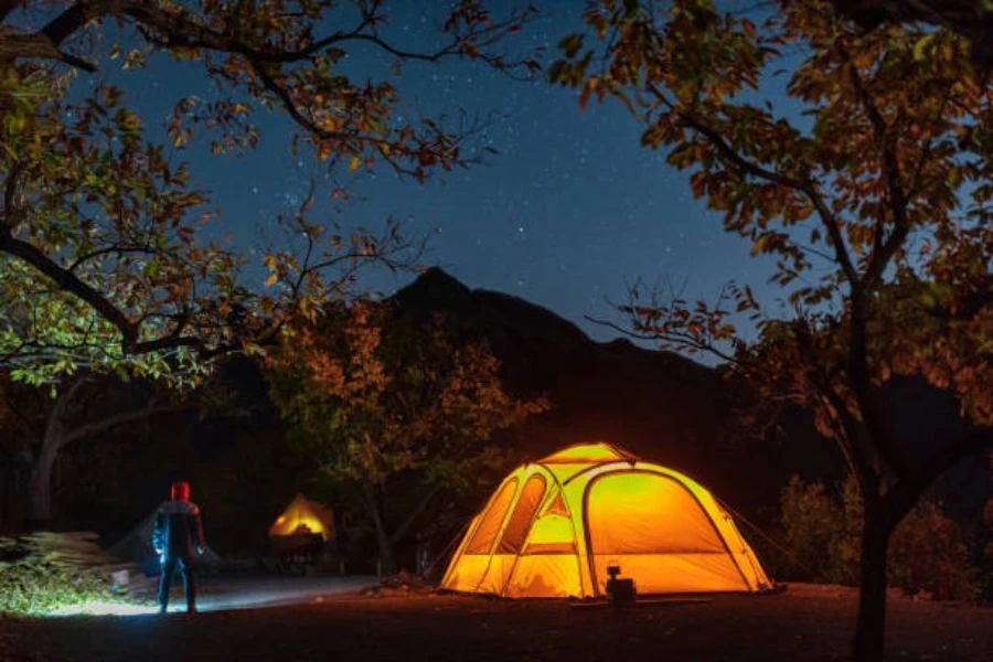 Una tienda de campaña con luces de camping instalada de noche.