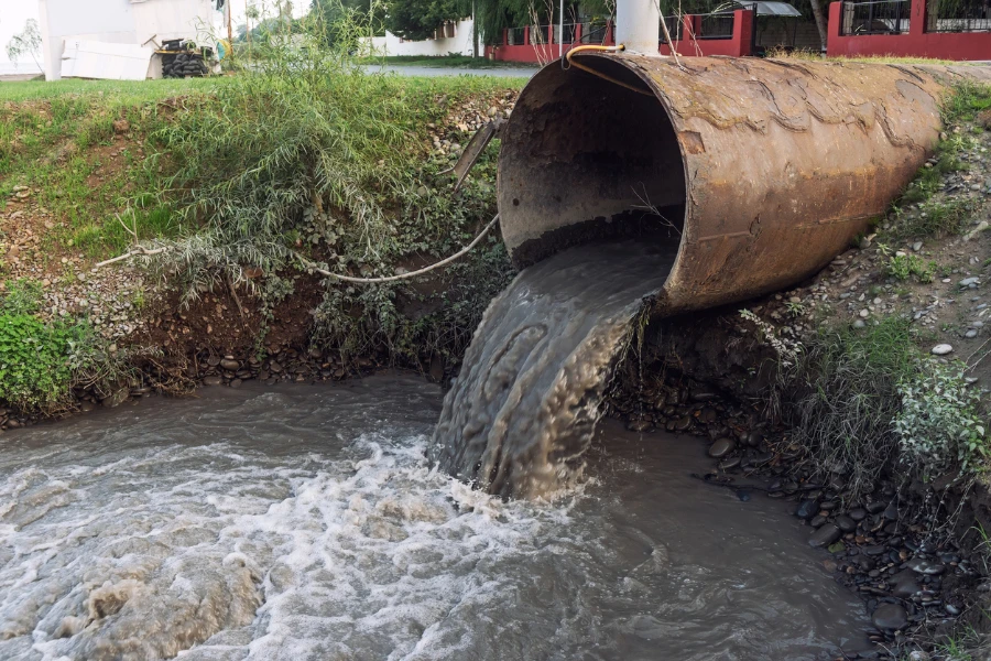 Polluted water flowing from pipes into a river