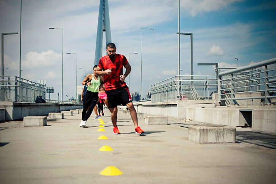 Runners using round agility cones for training on concrete