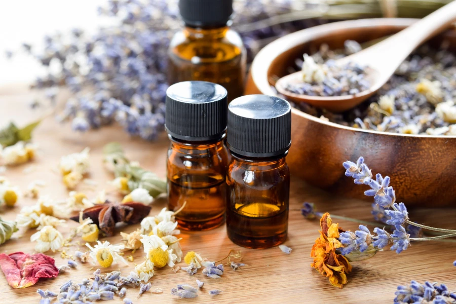 Selection of essential oils with herbs and flowers in the background