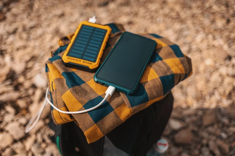 An eine solarbetriebene Batteriebank angeschlossenes Smartphone, das auf einem Rucksack sitzt