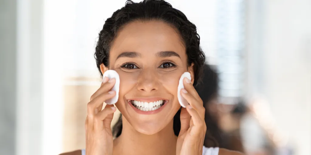 Smiling woman rubbing two facial pads against her cheeks
