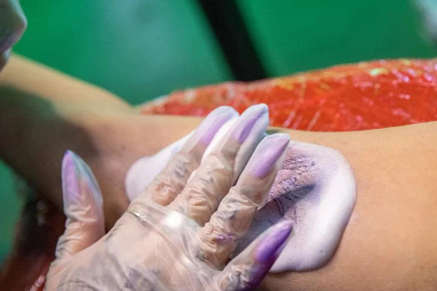 Tattoo artist applying tattoo foam soap to freshly tattooed arm