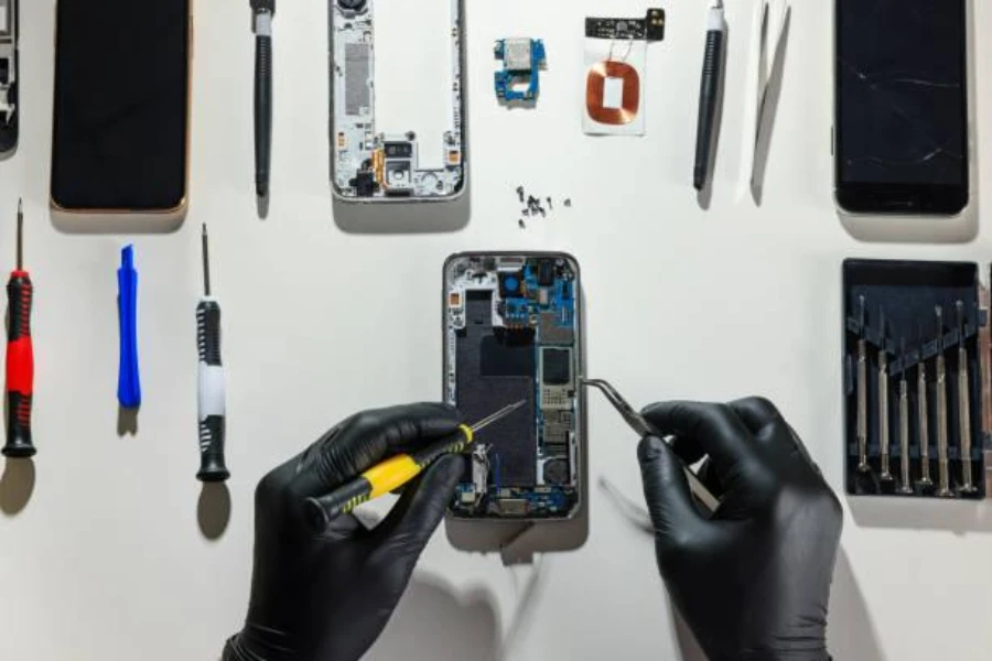 Technician repairing broken smartphone with phone repair tools
