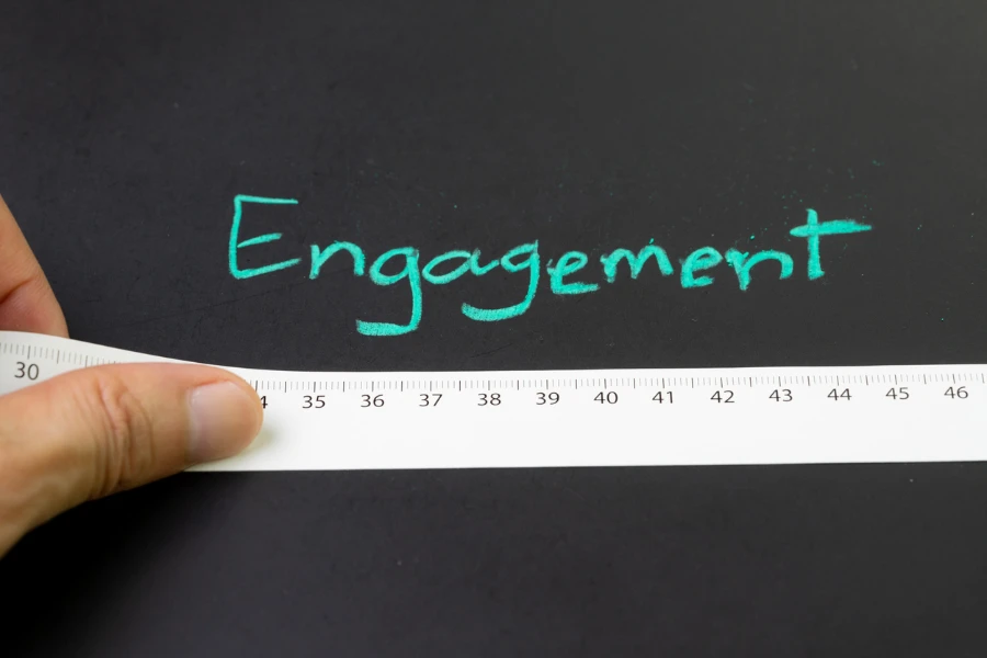 The word engagement written on a chalkboard with a person measuring the word