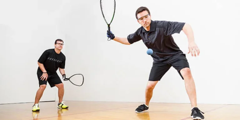 Two men playing squash wearing clear squash goggles
