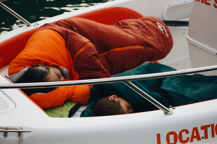 Two people sleeping in sleeping bags in a boat