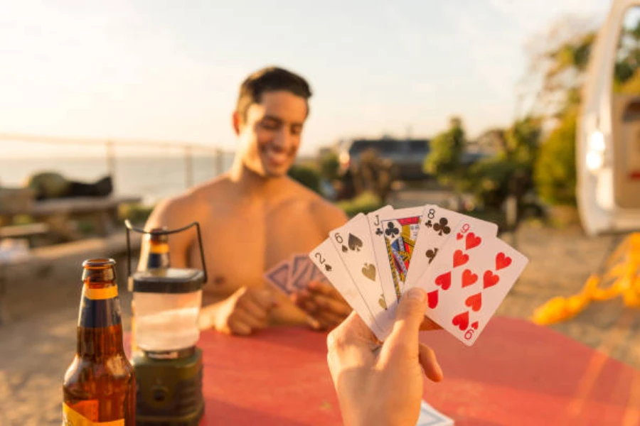 Two people using waterproof plastic playing cards outdoors in the sun