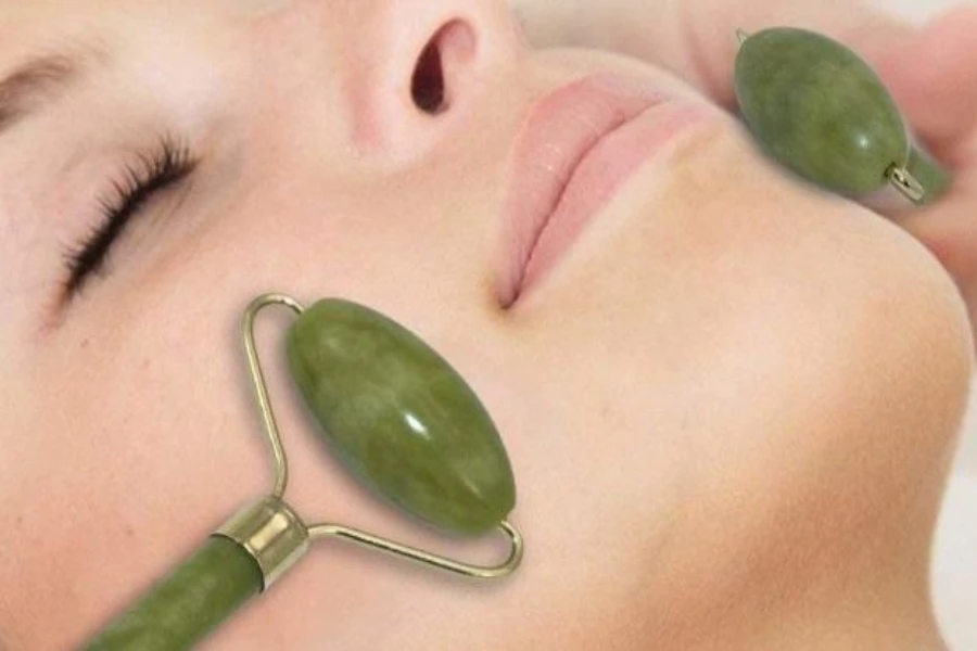 Woman undergoing facial massage with two translucent jade rollers