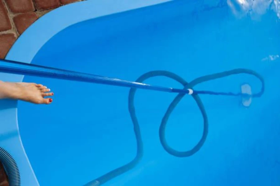 Woman using a vacuum head and hose to clean pool
