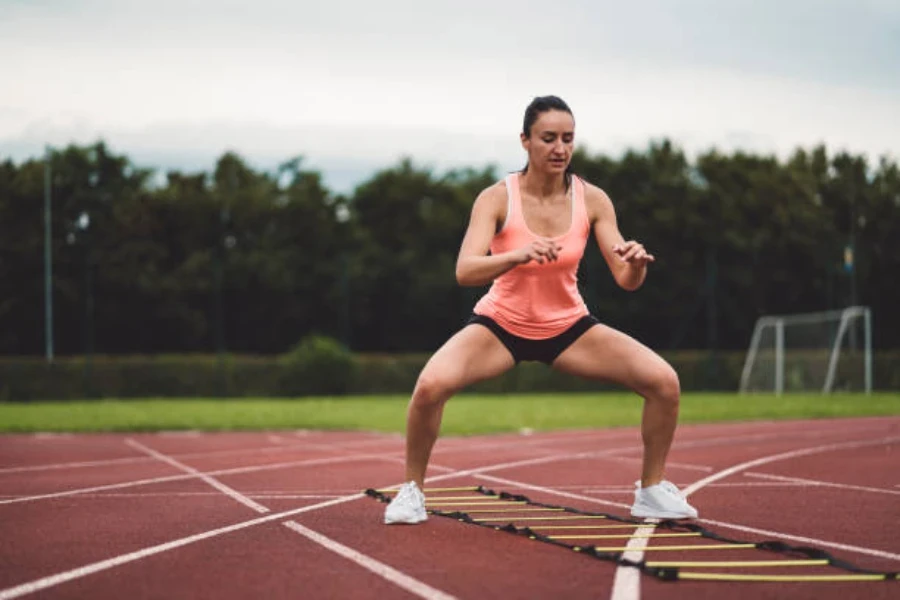 Donna che utilizza la scala di agilità su una pista da corsa all'aperto