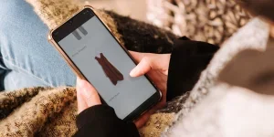 Woman using smartphone for online shopping sitting in armchair