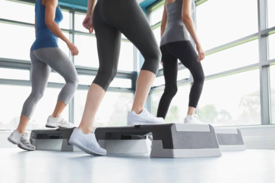 Mulher usando plataforma de degrau tradicional em uma aula de fitness