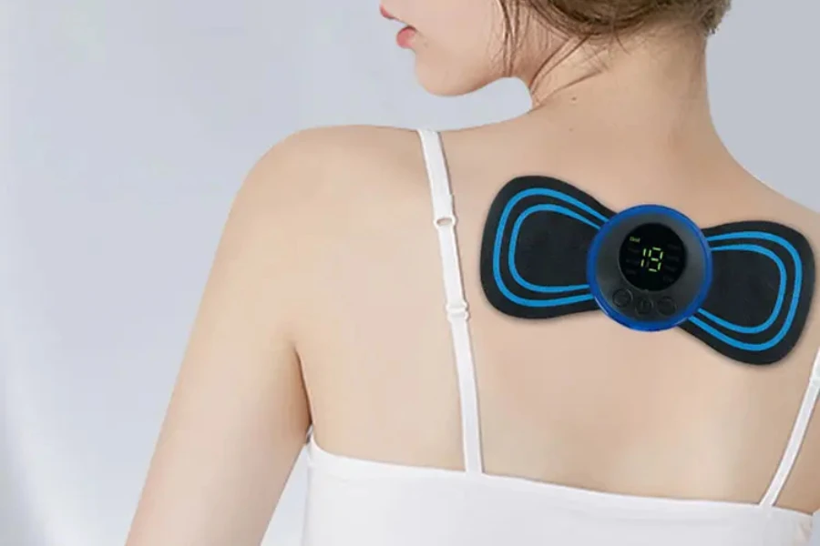 Woman wearing electric pulse neck massager on upper back