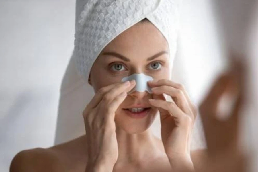 Femme avec une serviette sur la tête appliquant une bandelette nasale