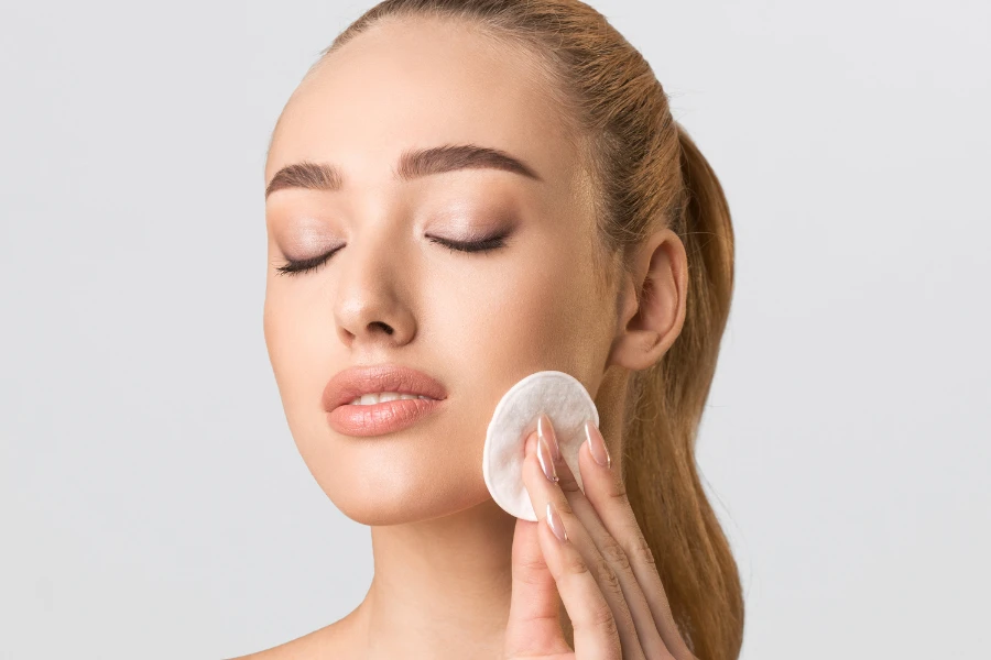 Woman with closed eyes using a facial cotton pad