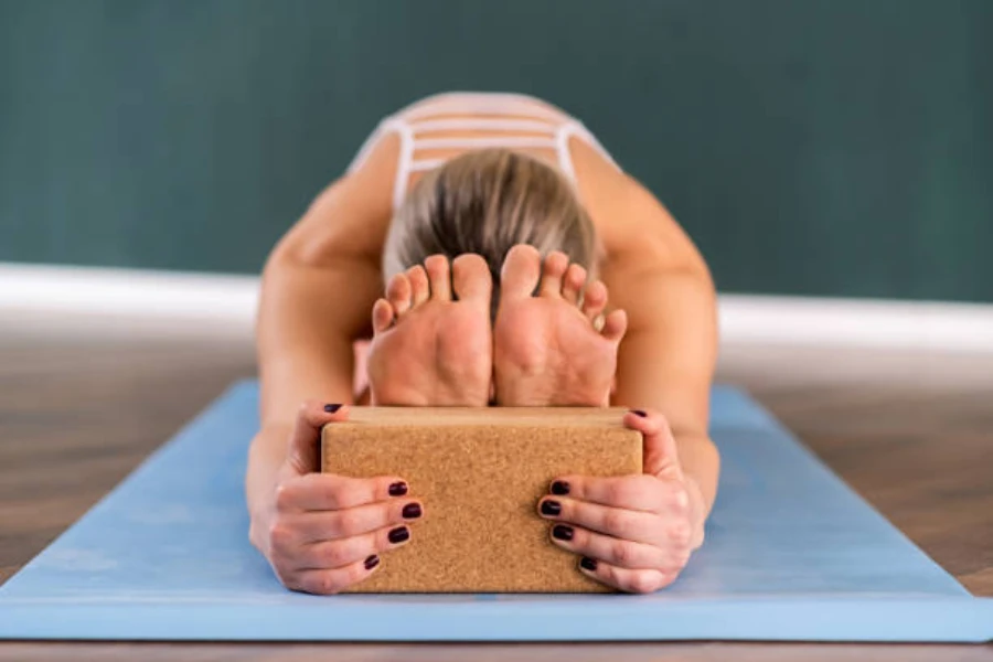 Woman with feet against cork yoga block holding a stretch