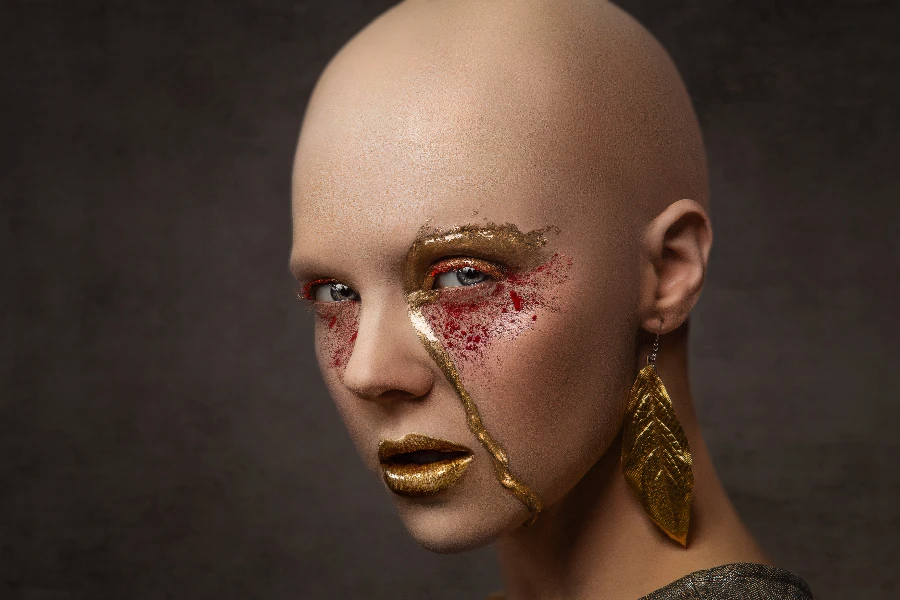 Woman with shaved head wearing asymmetrical goal makeup