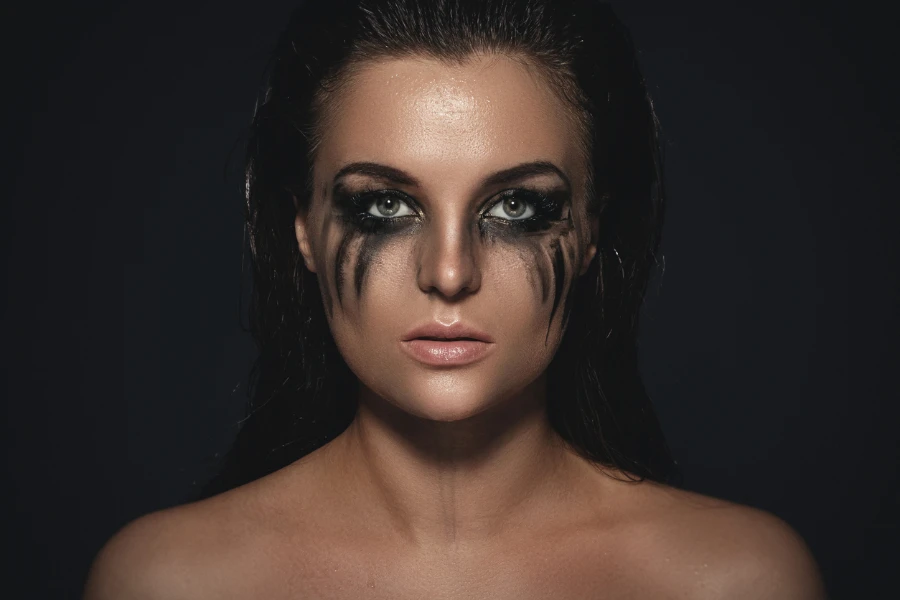 Woman with smudged black makeup under their eyes to make it look like they’ve been crying
