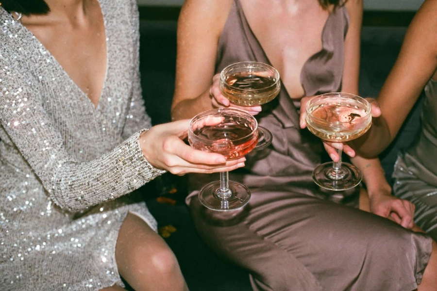 women holding champagne coupe with drinks filled in them