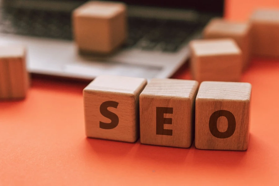 Wooden blocks spelling out SEO in front of a laptop