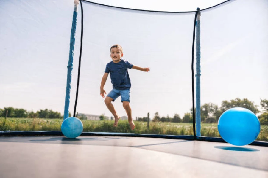 Young boy jumping in an enclosed trampoline with balls around him
