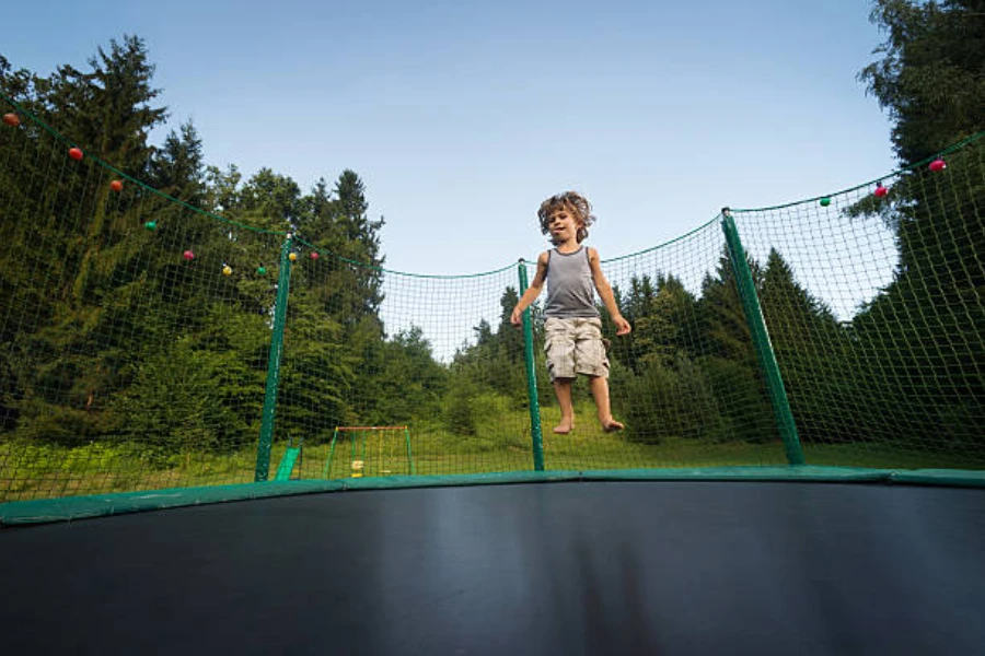 Young boy jumping in the middle of enclosed trampoline outdoors