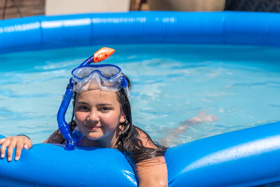 Young girl leaning against a large blue inflatable pool