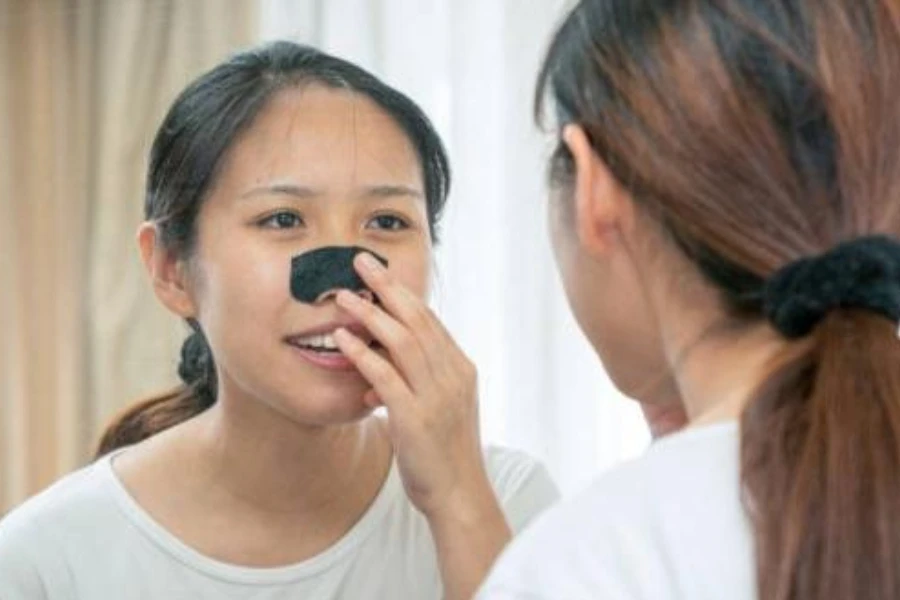 Young lady applying a nose strip while looking in the mirror